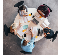 People sitting in a circle with books on table