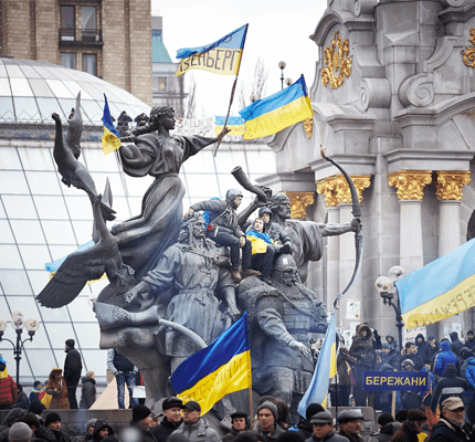 People sit on the monument decorated with flags in the center of Independence Square. Anti-governmental and pro-European integration protests.